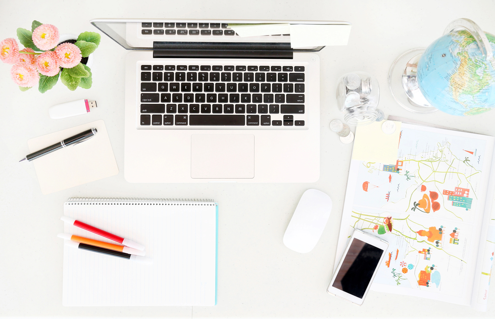 Overview of a desk space with laptop and globe for worldwide work from home jobs