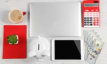 Still life shot of a work at home freelancer's desk, showing a laptop, calculator, and cash