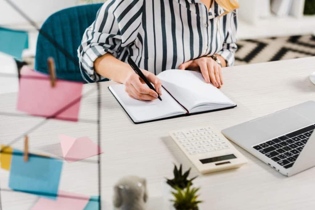 A virtual banker working from home at a desk with a laptop and calculator.