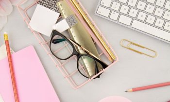 Still life of a home office desk, with a keyboard, glasses, and notebooks for blog post: remote jobs that pay $30 per hour