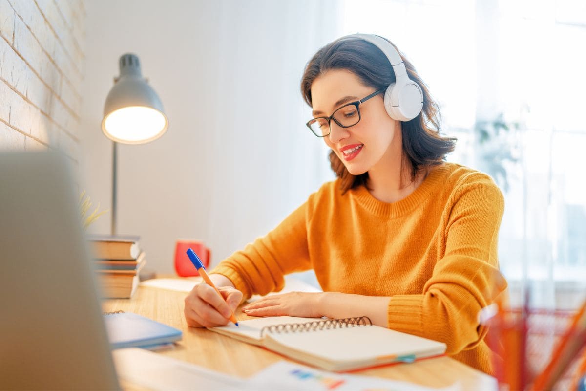 Woman working at home and writing in a notebook at a desk.