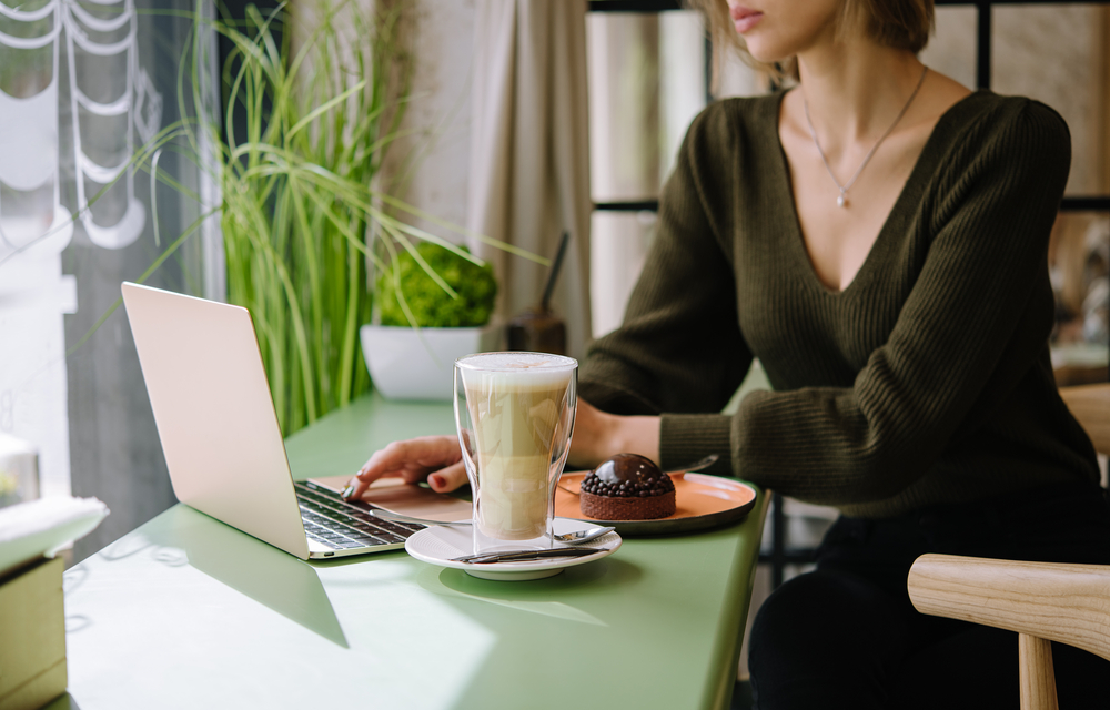 Small business owner using her laptop drinking a latte in a cafe