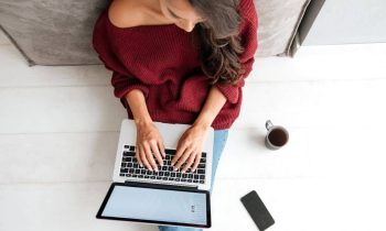 Woman with anxiety sitting on the floor and working from home on a laptop.