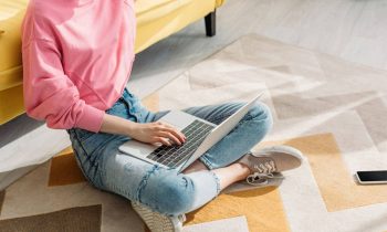 Woman sitting on the floor in her living room, working from home on a laptop for UserTesting