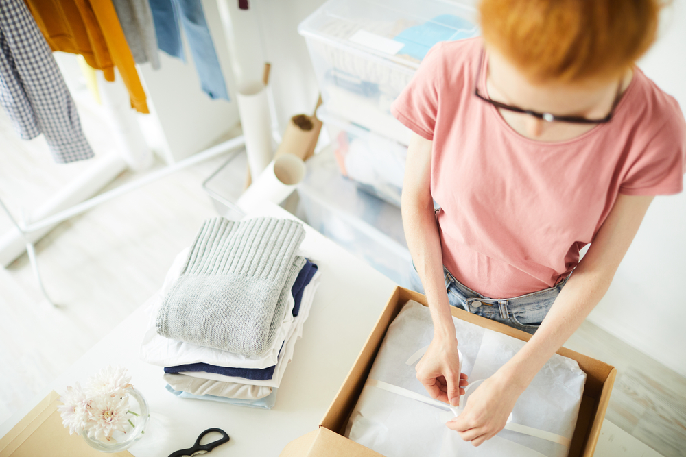 Woman at home packing up clothes she is selling online