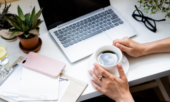 Woman holding cup of coffee studying her work at home courses on her laptop