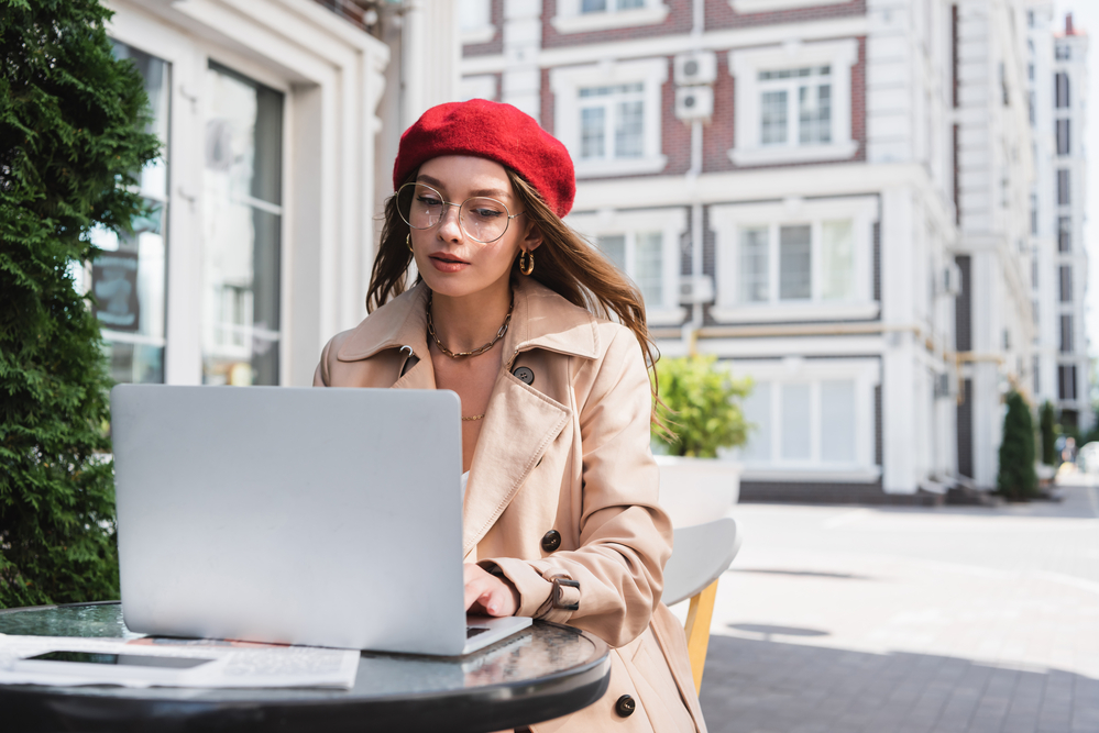 Woman wearing beret working on translation tasks on her laptop in France