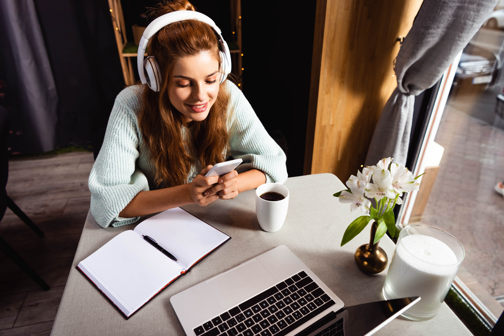 Woman wearing headphones reading an Appen review on her smartphone