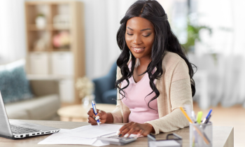 Woman with calculator and papers working from home as a bookkeeper