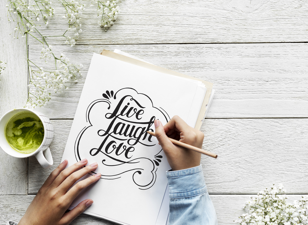 Woman working at home doing her handwriting job and drinking matcha