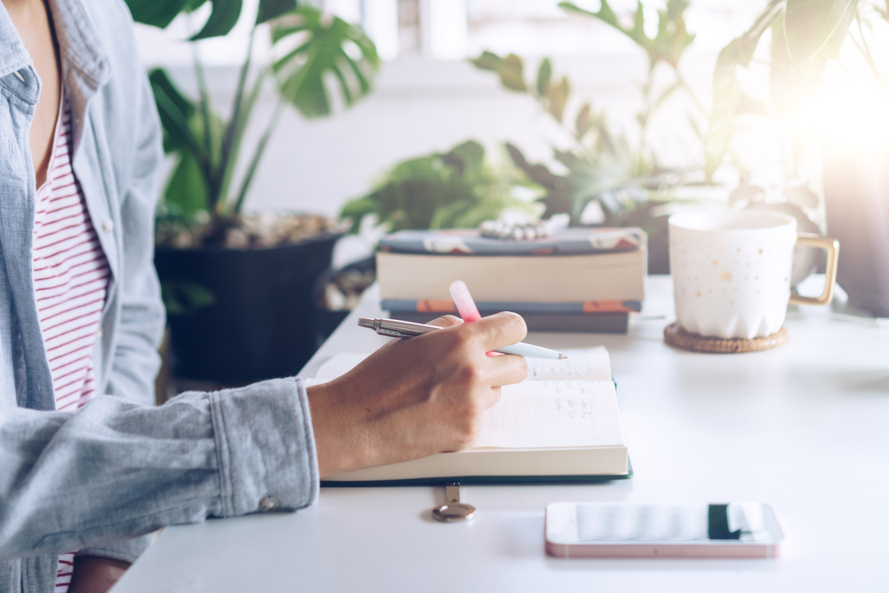 woman writing in her notebook figuring out ways to make an extra $2,000 per month