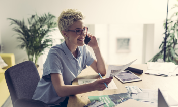 woman with short hair and glasses taking on phone working from home
