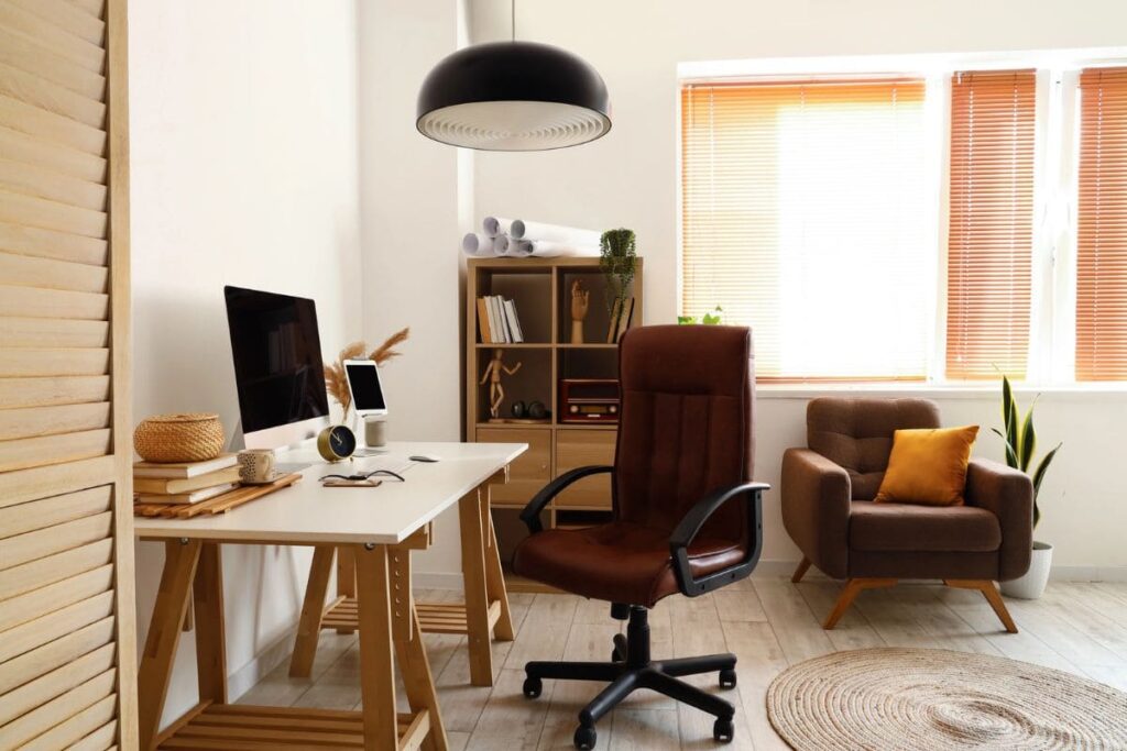A home office setup, with a desktop computer, webcam, ergonomic chair, and a bookshelf.