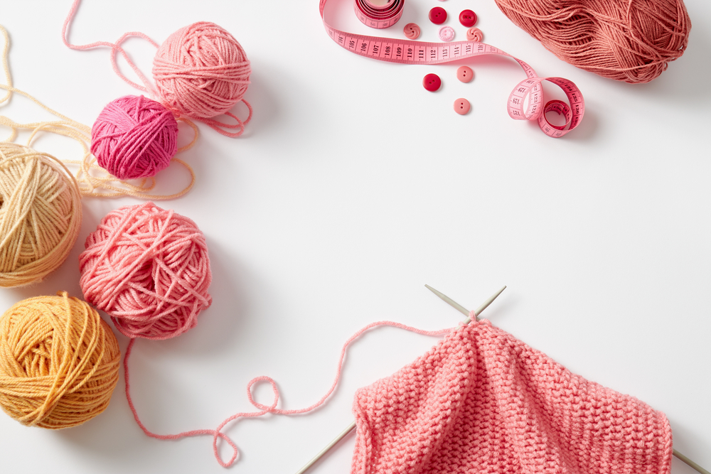 Yarn kintting needles buttons and a measuring tape sitting on a table