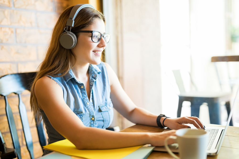 Young woman doing transcription work on her laptop at home