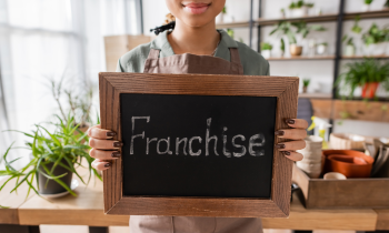 Young woman holding a chalkboard with the word franchise on it