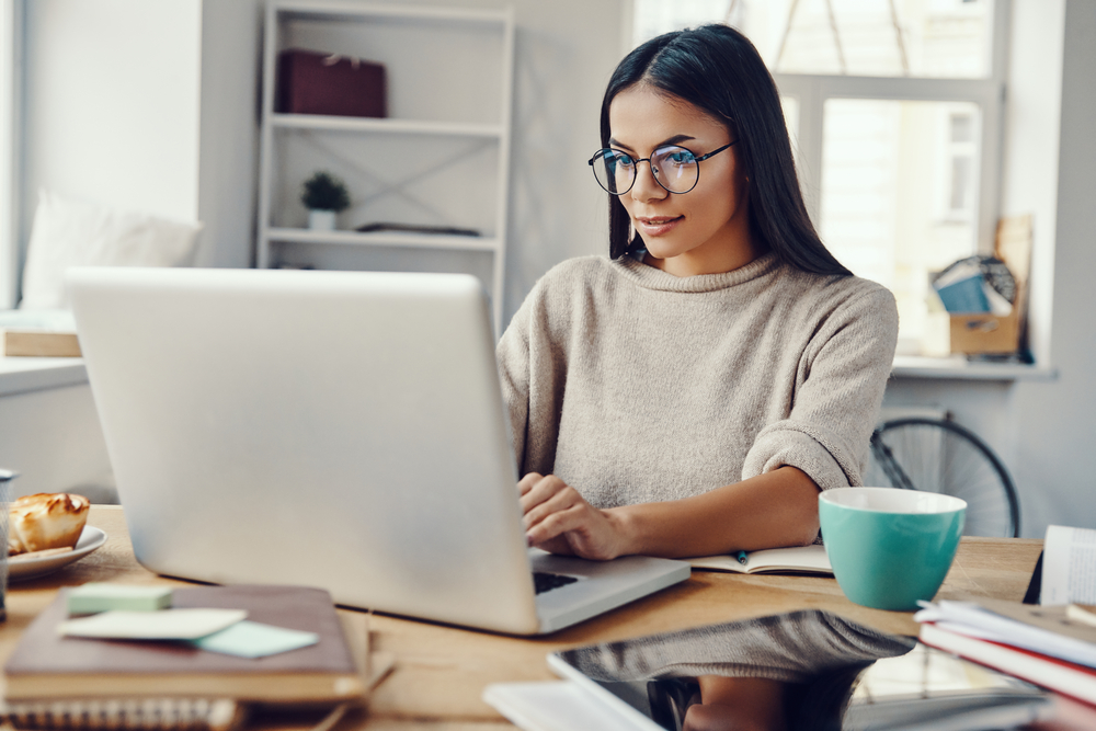 Young woman wearing glasses working on laptop in a remote HR job