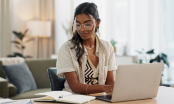 Young woman with glasses working on her laptop signing up and getting free money