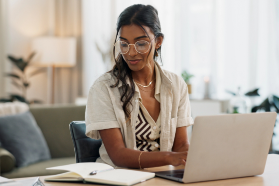 Young woman with glasses working on her laptop signing up and getting free money