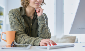 Young woman with painted finger nails working on her blog from home for post how to start a blog