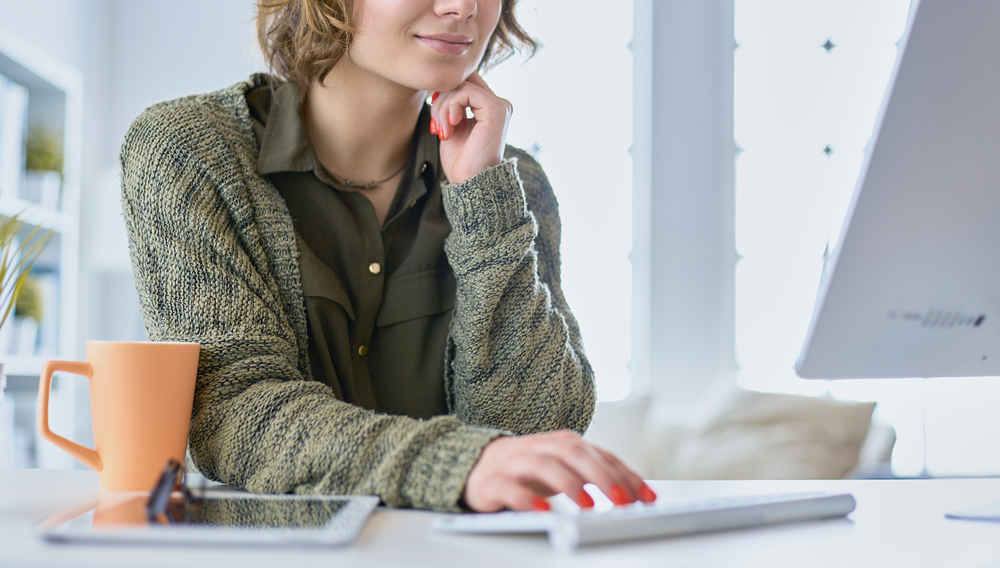 Young woman with painted finger nails working on her blog from home for post how to start a blog