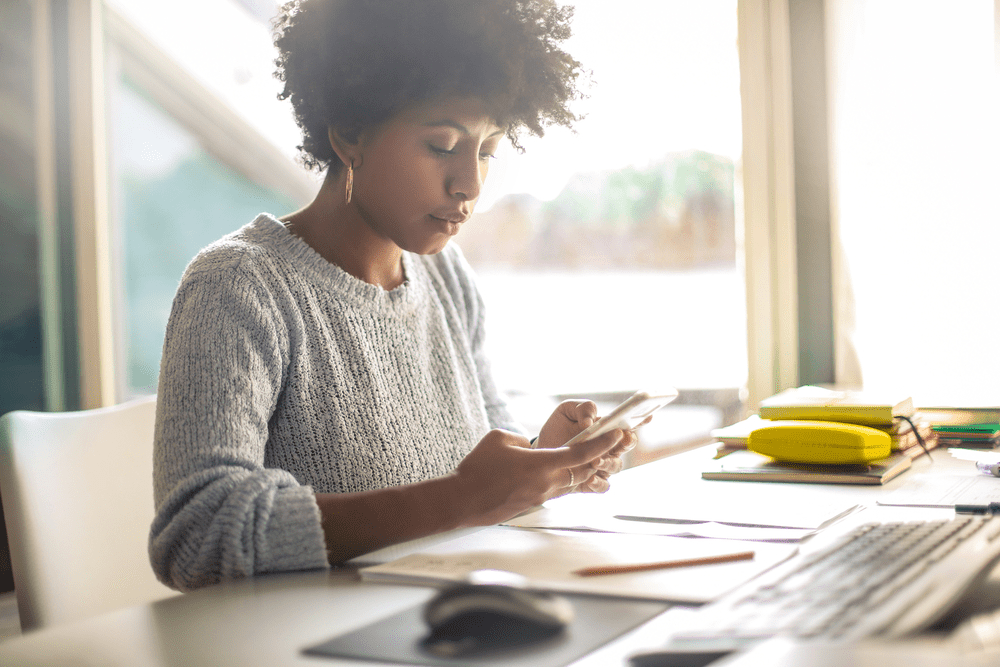 Young working at home texting someone on her phone