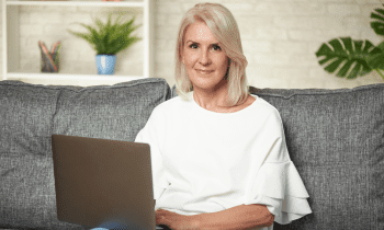 woman in her 50s sitting on sofa working with her laptop